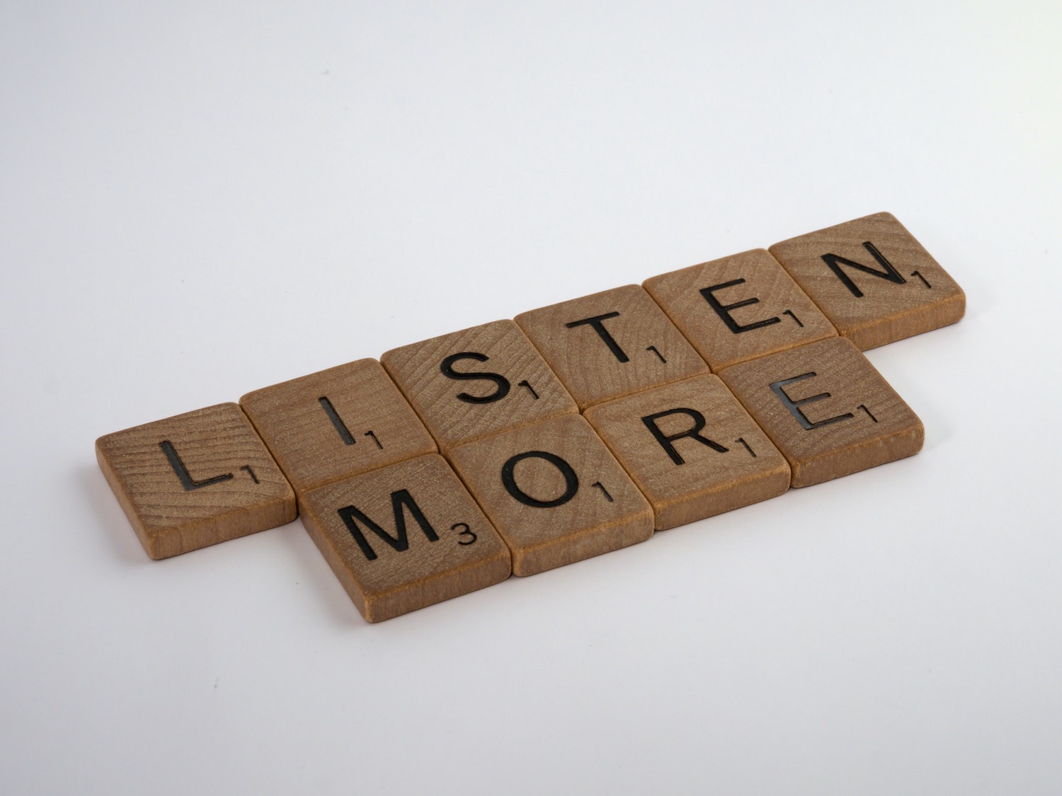 Scrabble pieces spelling out “listen more”